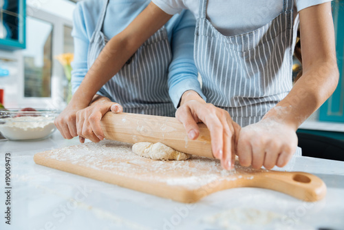 Baking with joy. Loving sweet little daughter making some dough and her mom helping her and they wearing aprons © Viacheslav Yakobchuk