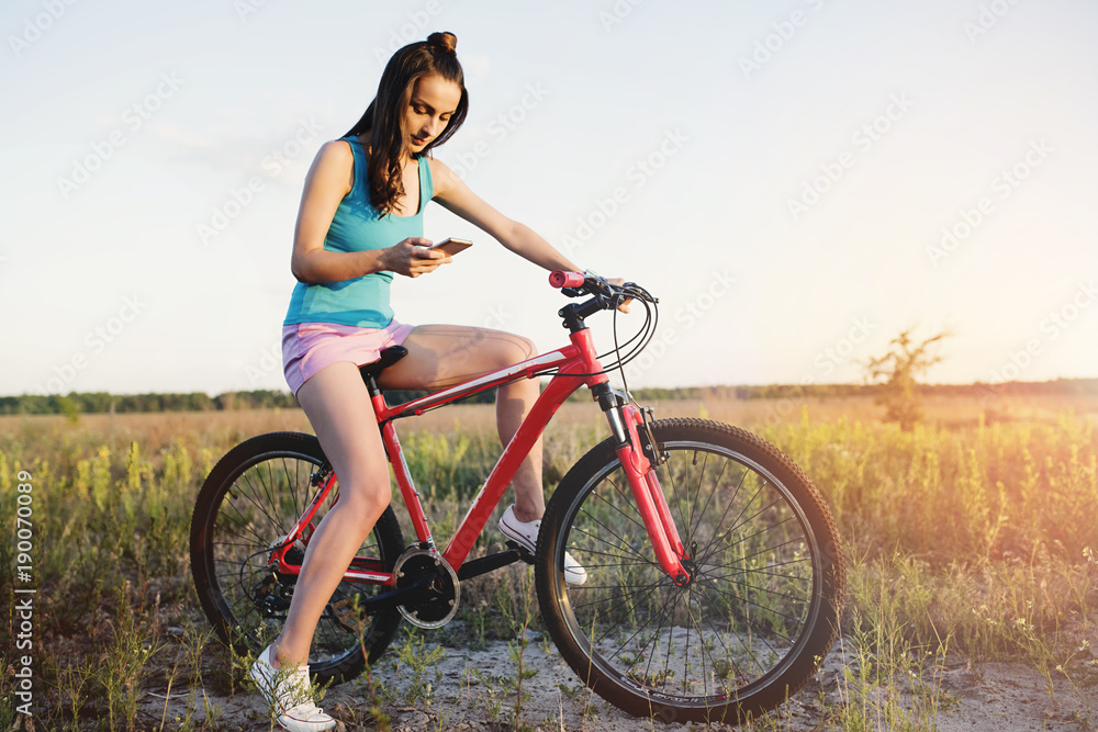With technology, you will not get lost. A girl on a bicycle selects a suitable route in the phone With technology, you will not get lost. A girl on a bicycle selects a suitable route in the phone