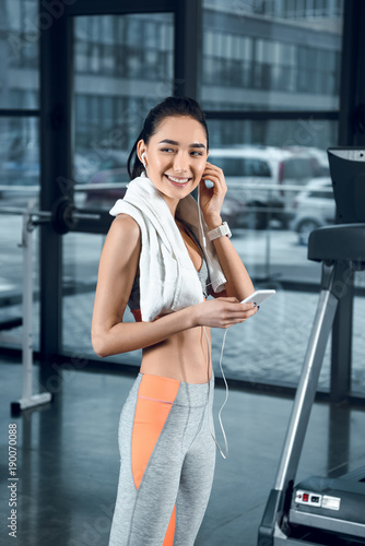 young sporty woman listening music with earphones at gym