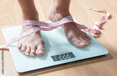 Healthy diet, fitness and weight loss concept. The legs of a young woman on the scales. Measuring tape. Checking the weight.