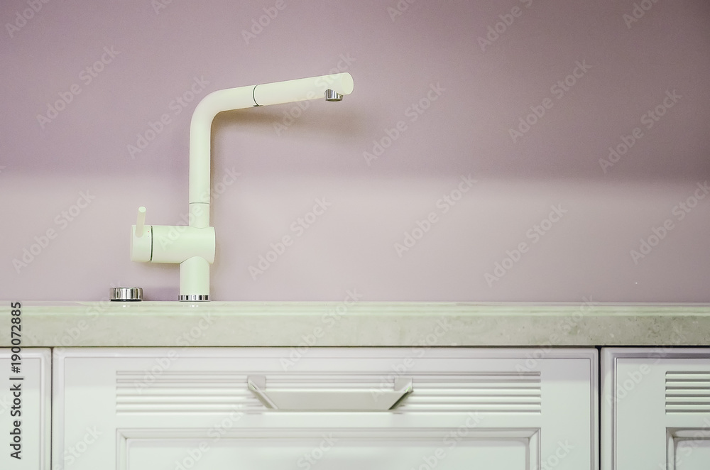 A new white kitchen sink made of artificial stone and a faucet. The concept of modern kitchen interior. A new white kitchen sink made of artificial stone and a faucet. The concept of modern kitchen interior.