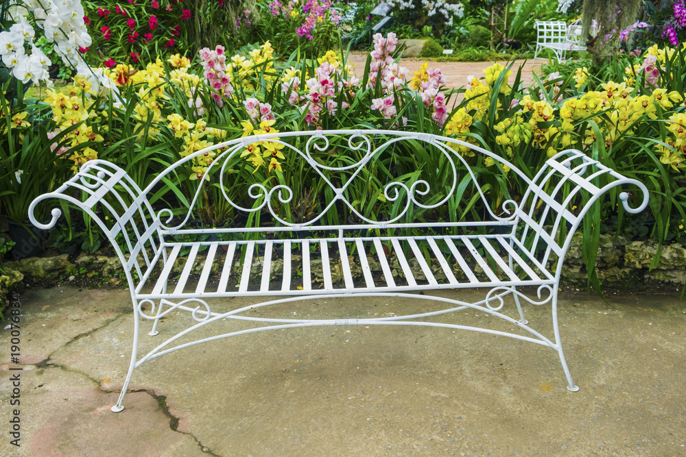 White iron bench in Multi-Color Orchids flower garden.