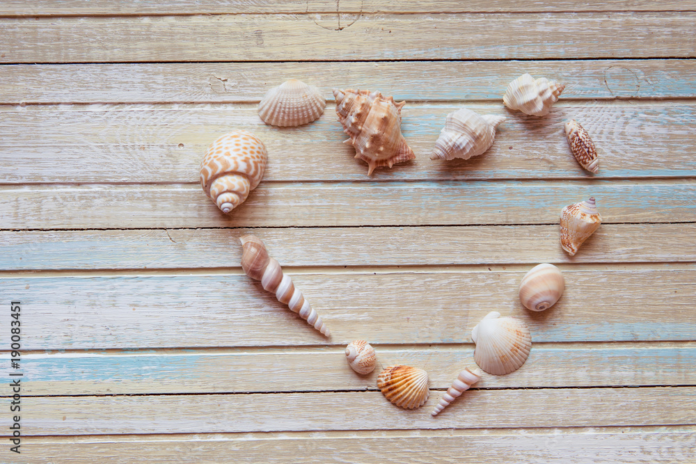 Seashells shaped heart on a wooden background top view Seashells shaped heart on a wooden background top view