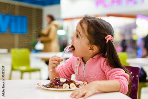 toddler girl eating in outdoor cafe