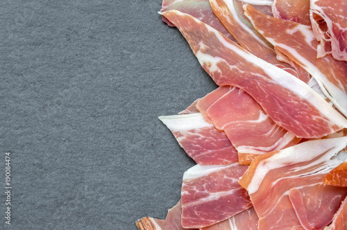 slices of serrano ham on dark background