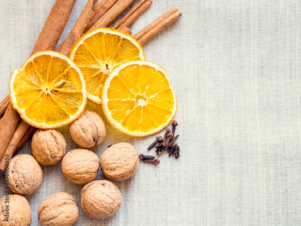 Orange, nuts, cinnamon and carnation on linen background with Christmas atmosphere Orange, nuts, cinnamon and carnation on linen background with Christmas atmosphere