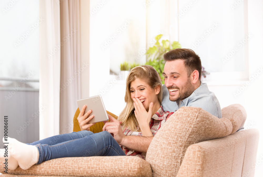 Young couple looking at tablet and laughing at home Young couple looking at tablet and laughing at home