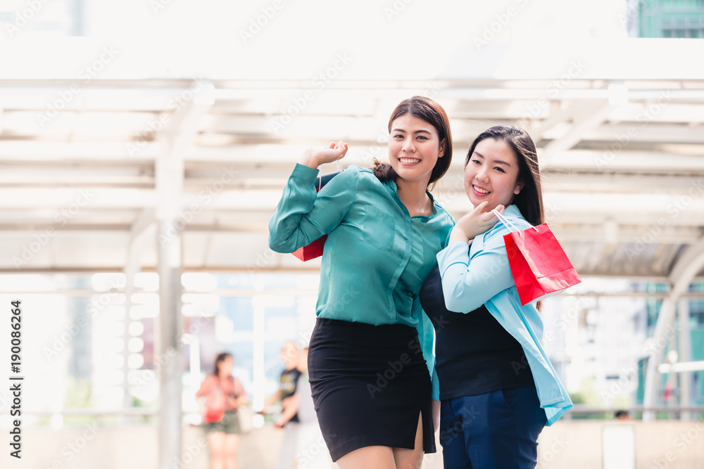 Beautiful girls and friend in city holding shopping bags