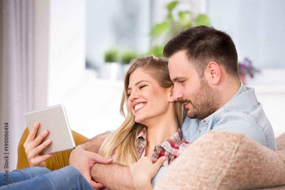 Young couple looking at tablet and laughing at home Young couple looking at tablet and laughing at home