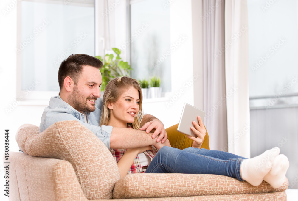 Young couple looking at tablet at home Young couple looking at tablet at home