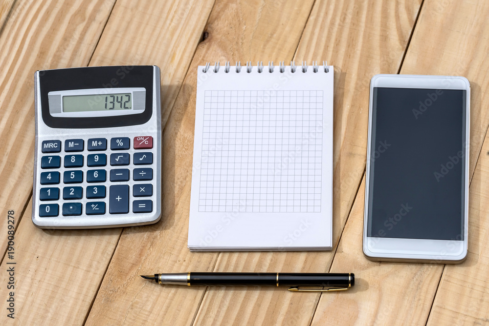 Smartphone with notebook, pen and calculator on wooden table Smartphone with notebook, pen and calculator on wooden table