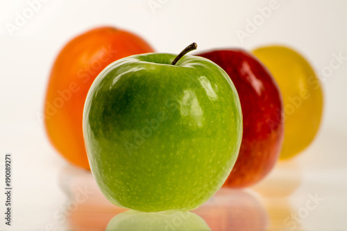  Intensywnie kolorowe i okrągłe - zielone jabłko z innymi owocami na białym tle