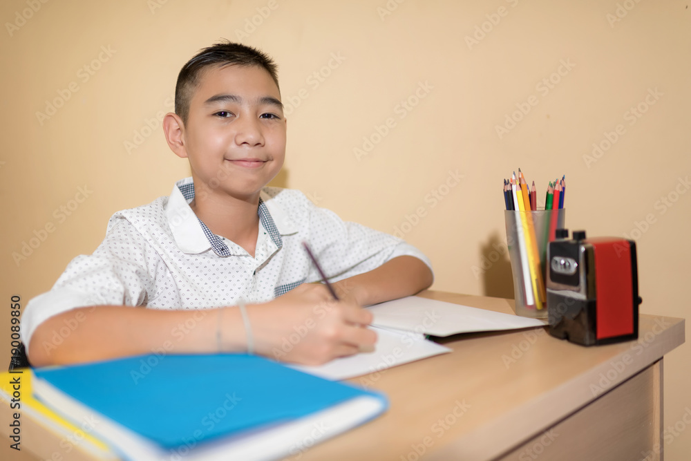 A Little Asian boy use pencil writing on notebook homework A Little Asian boy use pencil writing on notebook homework
