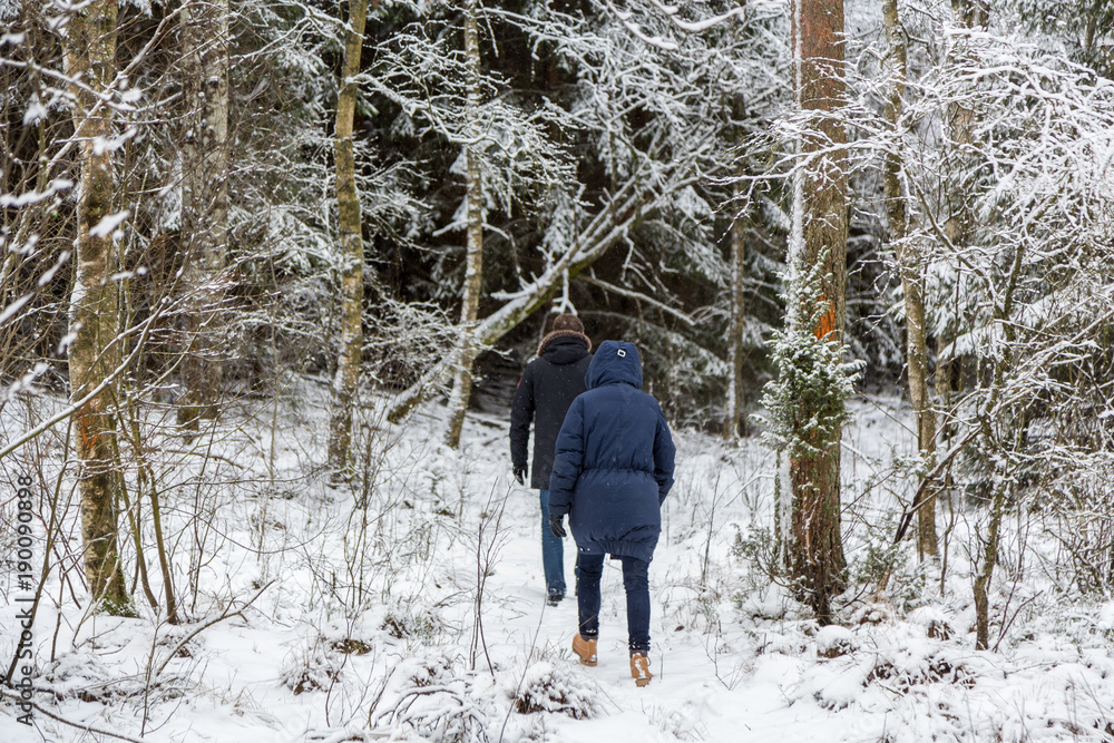 Man och kvinna vandrar i snötäckt skog