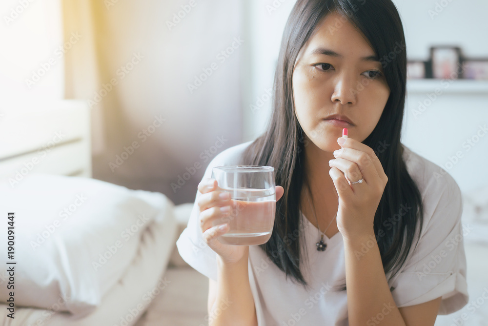Woman sick with capsules putting in her mouth,female taking medicines and a glass of water,Concept for health Woman sick with capsules putting in her mouth,female taking medicines and a glass of water,Concept for health