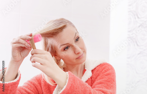 Bild auf Leinwand Pretty young woman wind the hair in curlers