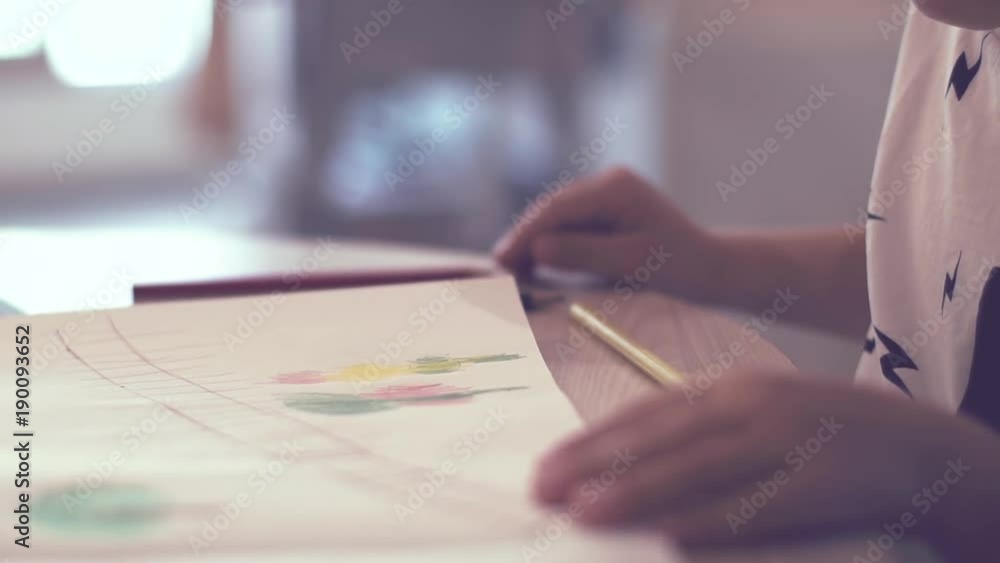 Close-up - The Hands Of An Unidentified Child Draw A Colored Drawing With Pencils Sitting At Table Next To An Unidentified Mother Helping Him Close-up - The Hands Of An Unidentified Child Draw A Colored Drawing With Pencils Sitting At Table Next To An Unidentified Mother Helping Him