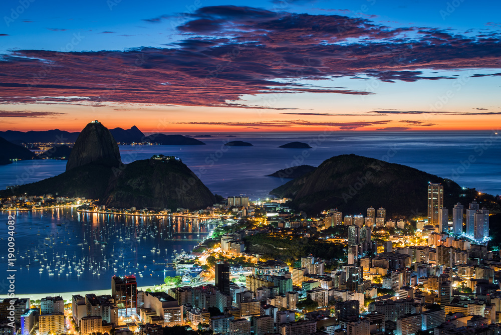 Fototapeta premium Rio de Janeiro city just before sunrise with city lights on, and the Sugarloaf Mountain in the horizon
