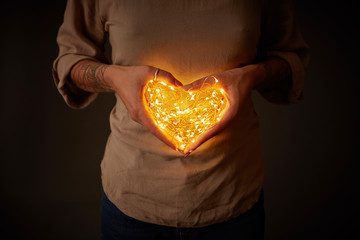 Woman holding lights in the shape of a heart