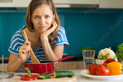 Bilde på lerret Dissatisfied Woman Cooking Dish in Sauce Pan