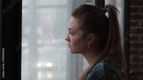 Close-up of a young sad woman looking out the window