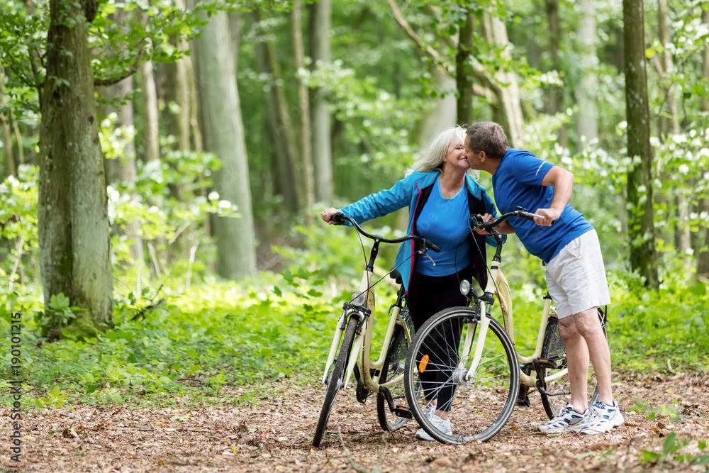 Naklejka premium Elderly couple kissing in the woods.