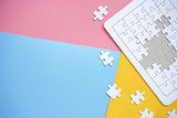 White jigsaw puzzle on blue, pink and yellow background.