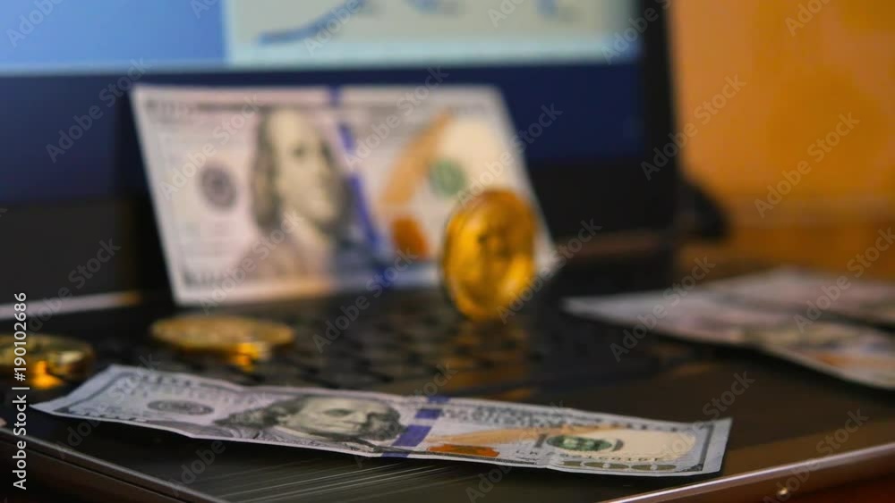 Bitcoin is a physical coin symbol and one hundred dollars on a laptop with a price chart background, a future concept of financial currency Bitcoin is a physical coin symbol and one hundred dollars on a laptop with a price chart background, a future concept of financial currency