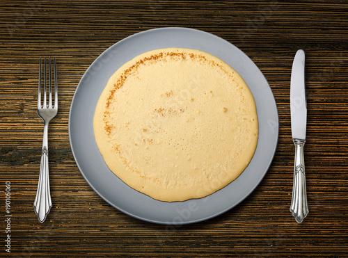 Perfect pancake on blue plate on textured wooden background..
