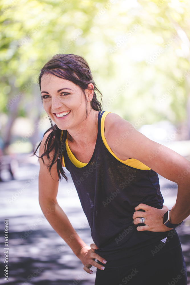 Beautiful brunette female fitness model running / stretching / exercising outside in a leafy and green suburb Beautiful brunette female fitness model running / stretching / exercising outside in a leafy and green suburb