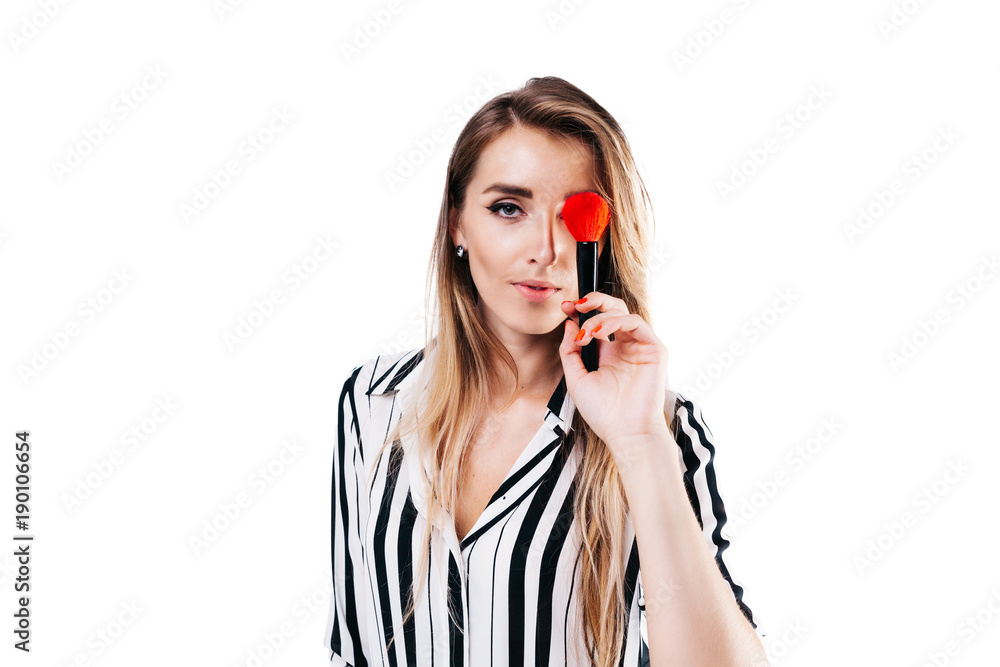 beautiful girl make-up artist with beautiful hair in a striped shirt on a white background in whose hands tassels and other makeup accessories beautiful girl make-up artist with beautiful hair in a striped shirt on a white background in whose hands tassels and other makeup accessories