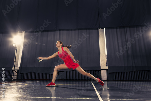 Young woman playing badminton at gym