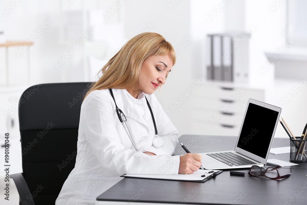 Female doctor filling up application form in consultation room Female doctor filling up application form in consultation room