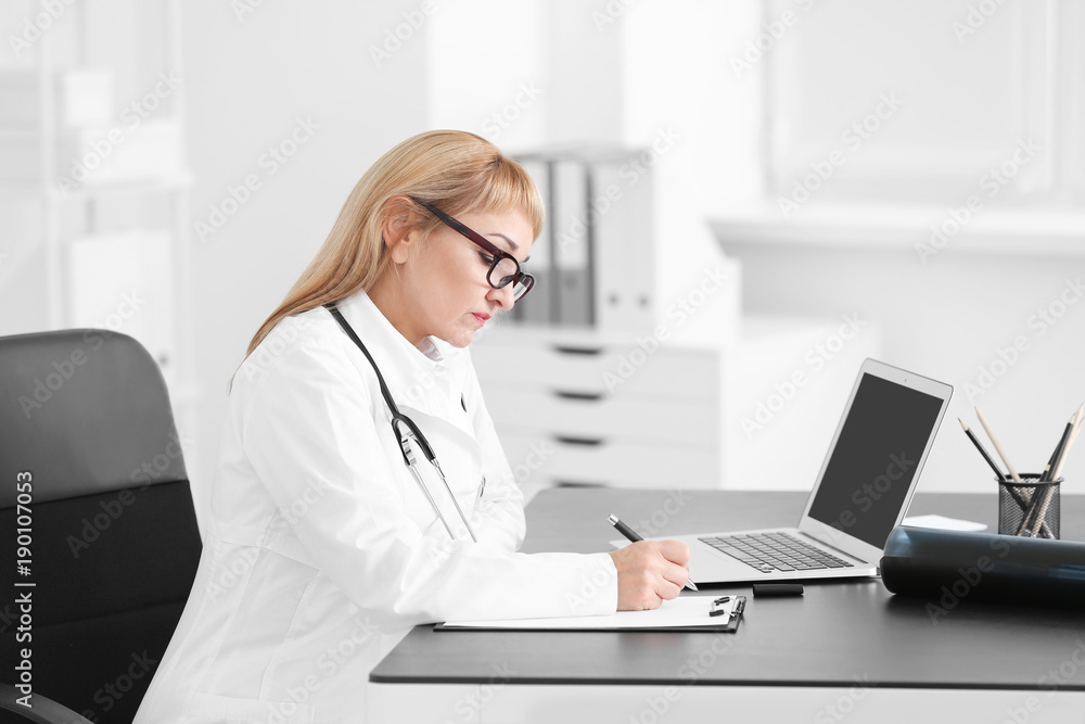 Female doctor filling up application form in consultation room Female doctor filling up application form in consultation room