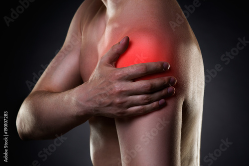 Man with pain in shoulder on black background