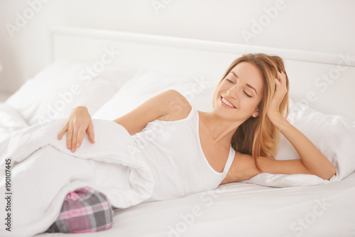 Young woman lying on white pillow in bed