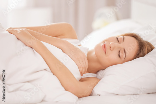 Young woman sleeping on white pillow in bed