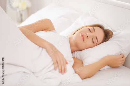 Young woman sleeping on white pillow in bed