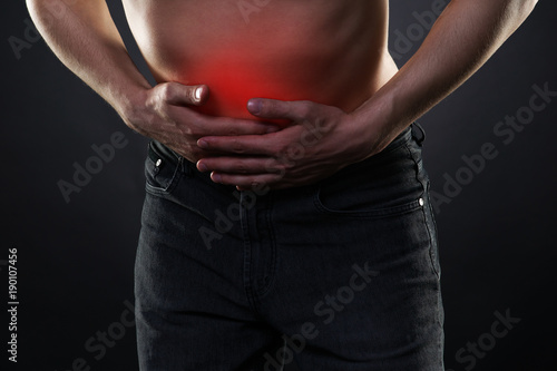 Man with abdominal pain, stomach ache on black background