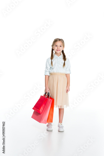 smiling child with shopping bags in hand isolated on white
