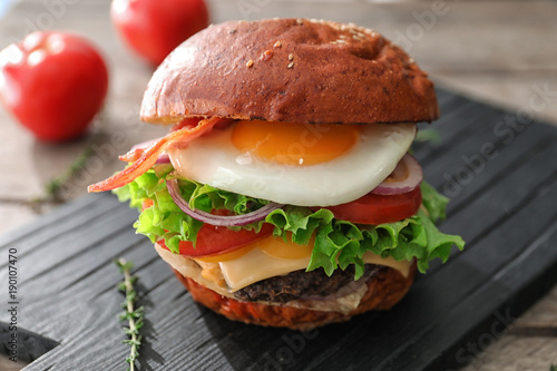Tasty burger with fried egg on table