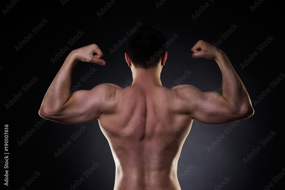 Handsome bodybuilder posing on black background, perfect muscular male back