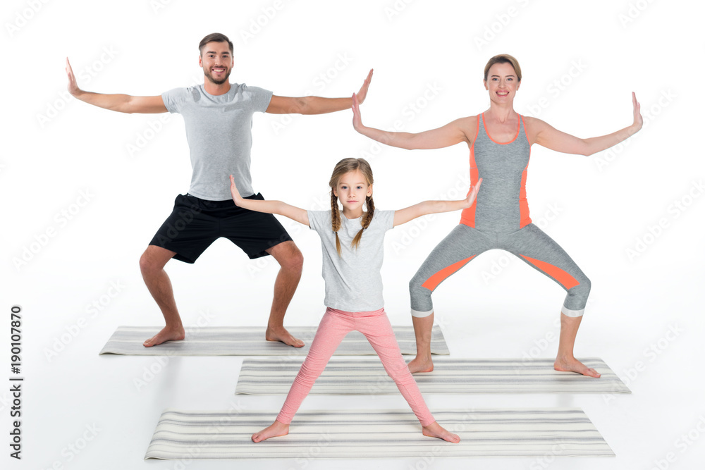 Obraz premium athletic family practicing yoga on mats together isolated on white