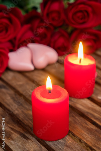 Two burning candles with fresh roses