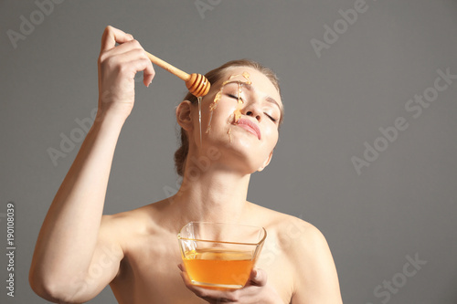 Young woman applying honey ...