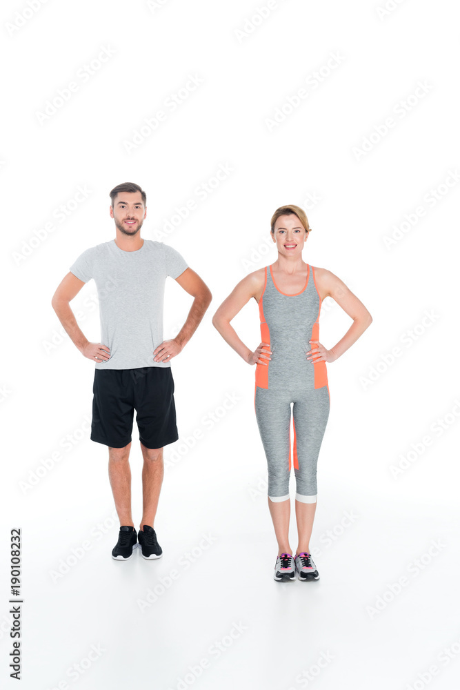 smiling couple in sportswear standing akimbo isolated on white smiling couple in sportswear standing akimbo isolated on white