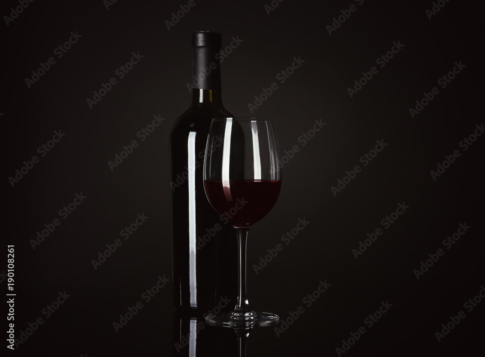 Bottle and glass with red wine on black background Bottle and glass with red wine on black background