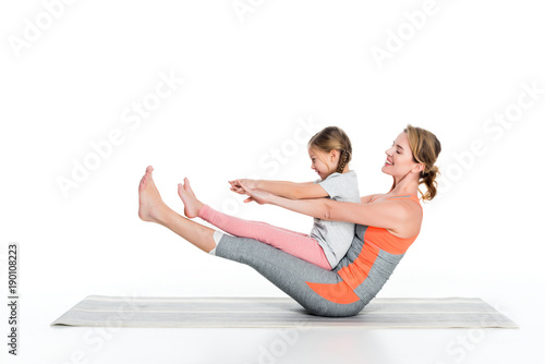 sportive mother and daughter exercising together isolated on white
