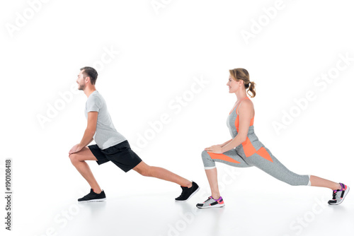 side view of sportive couple warming up before training isolated on white