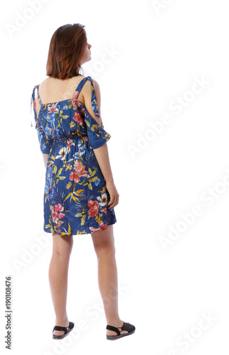 back view of standing young beautiful woman. girl watching. Rear view people collection. backside view of person. The girl in a colorful dress looks upstairs.